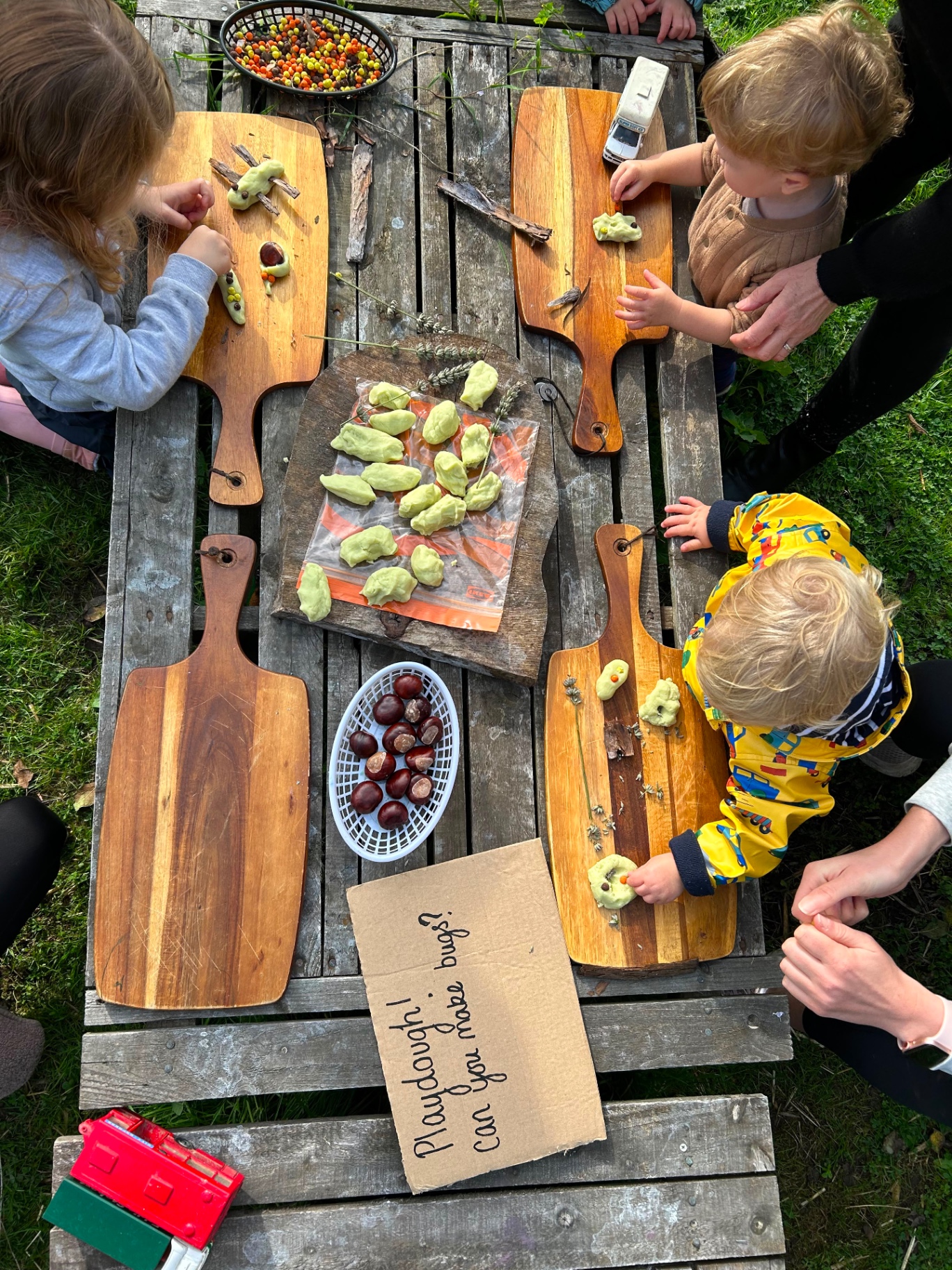 Children making playdough bugs at an outdoor table