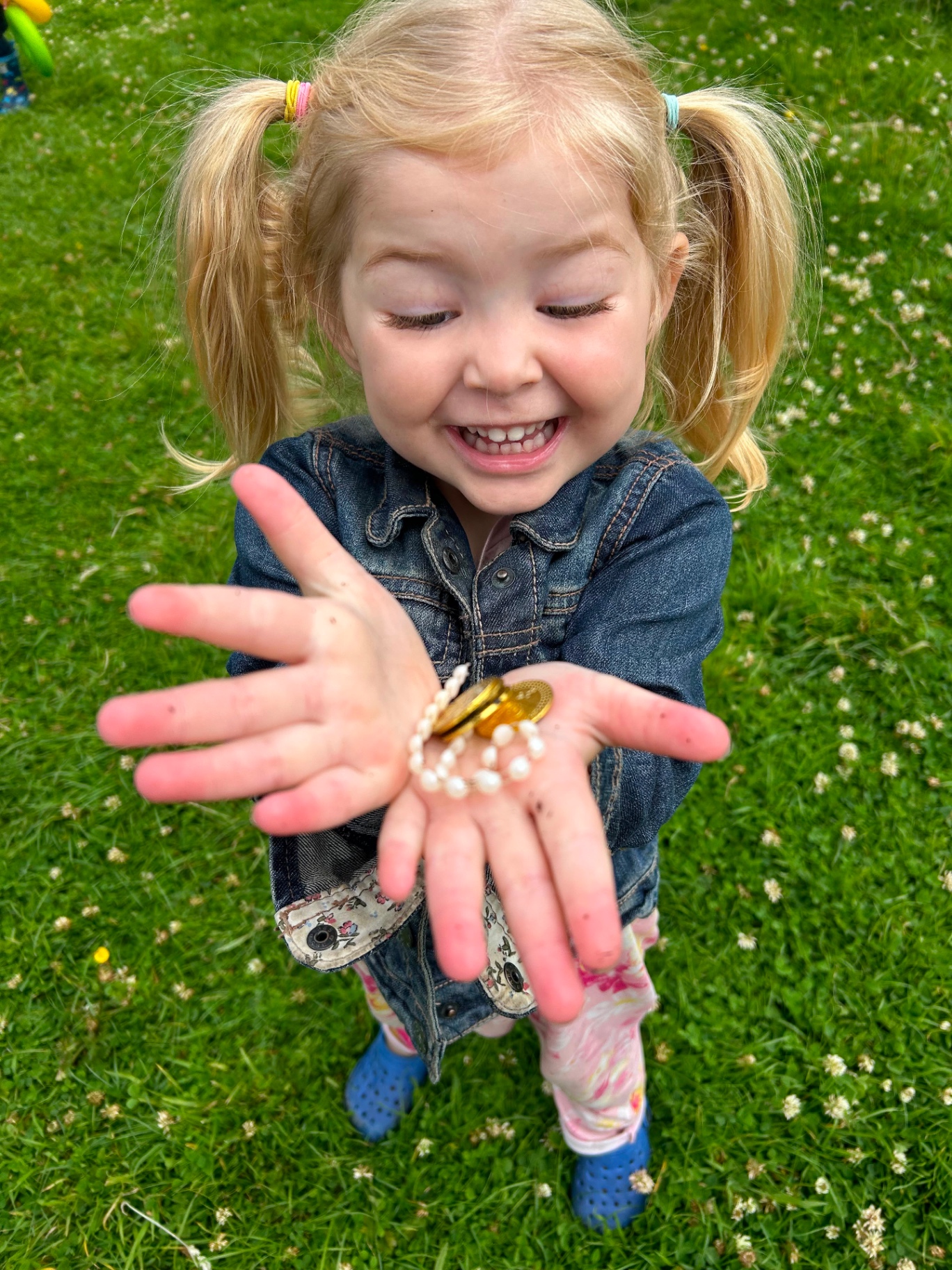 A little girl holding treasure she found in the grass