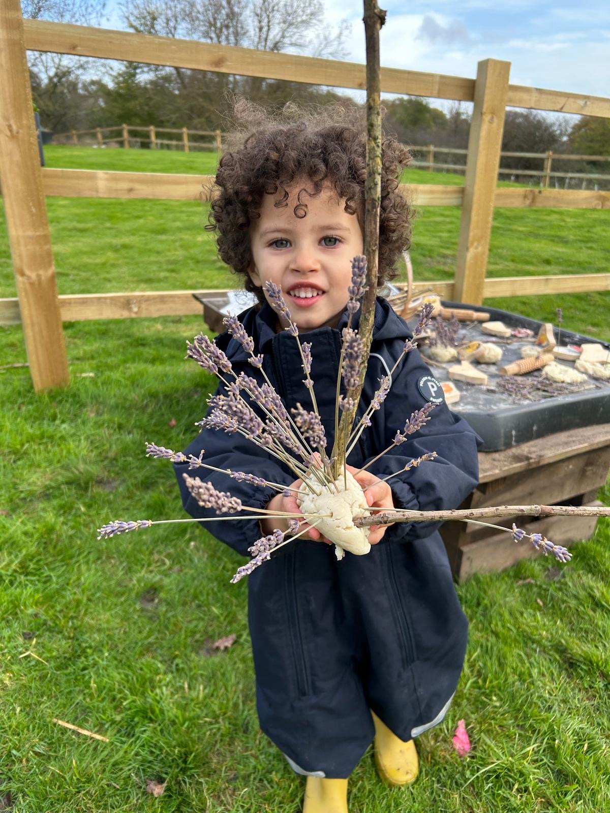 A child holding a dough hedgehog covered in lavender stalks